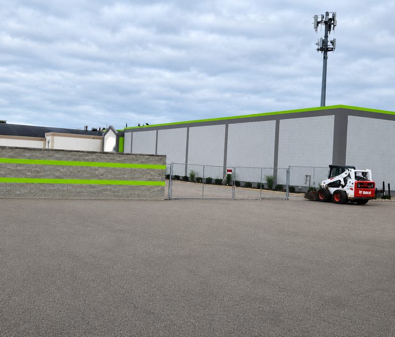 Self-storage building under construction behind a block wall